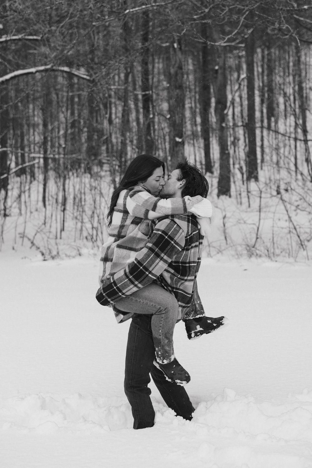 Romantic winter scene of a couple dancing in the snow surrounded by bare trees.