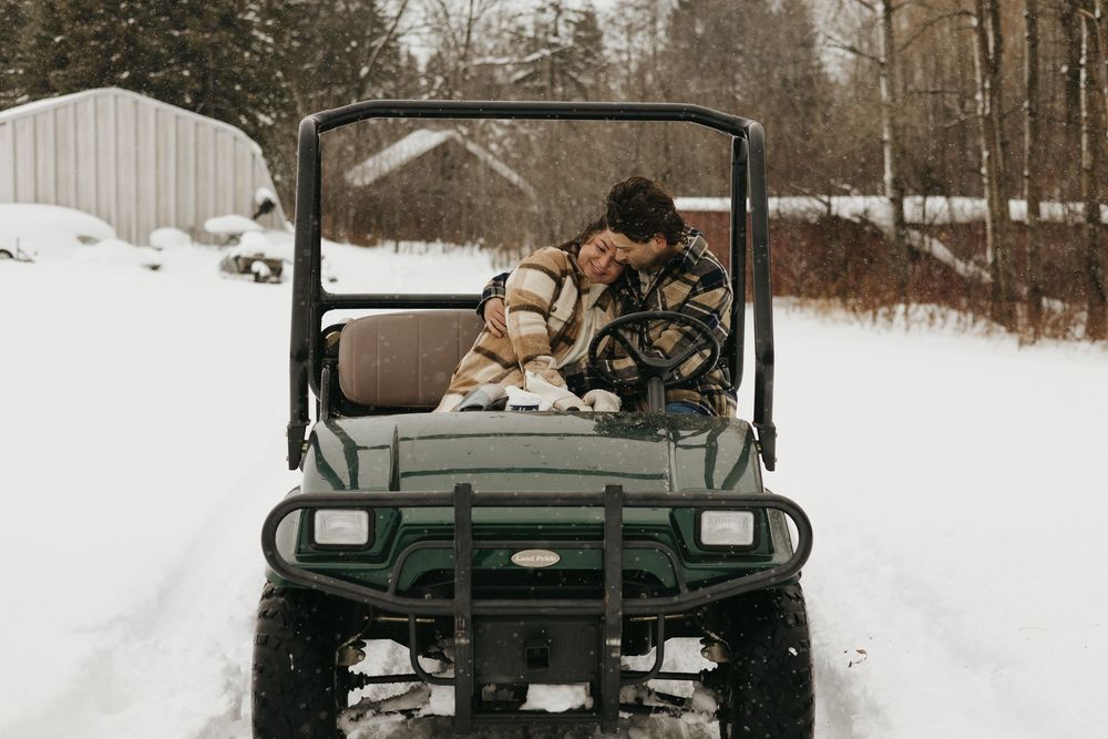 A utility vehicle loaded with firewood travels through a snowy winter landscape.