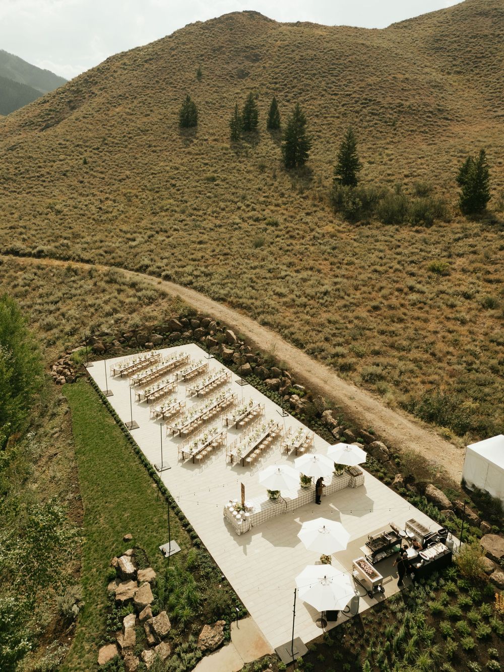 Aerial view of an outdoor wedding ceremony setup with white chairs arranged in rows on a mountaintop venue.