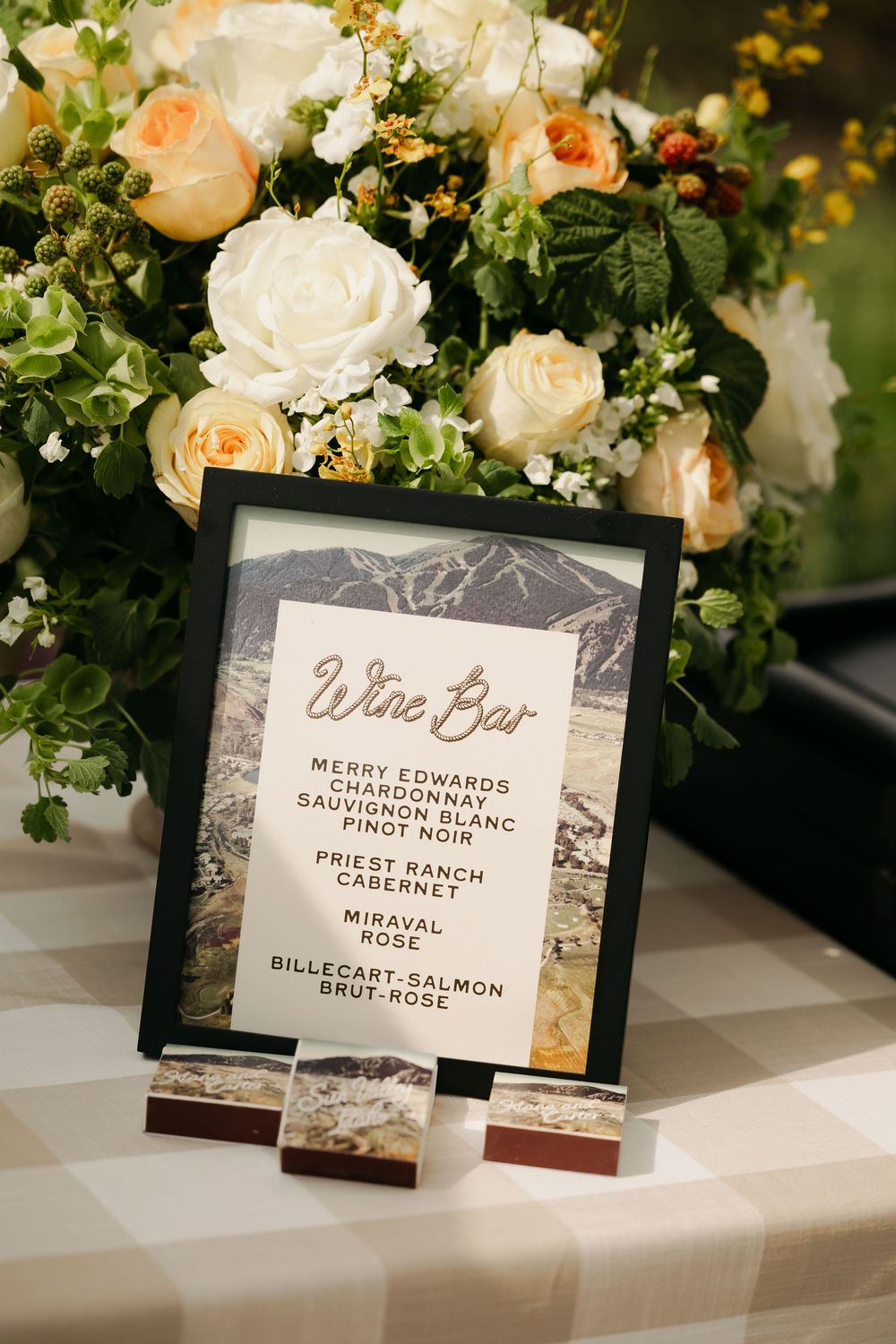 Elegant wedding reception signage with wine bar and menu cards displayed alongside peach and white floral arrangements.