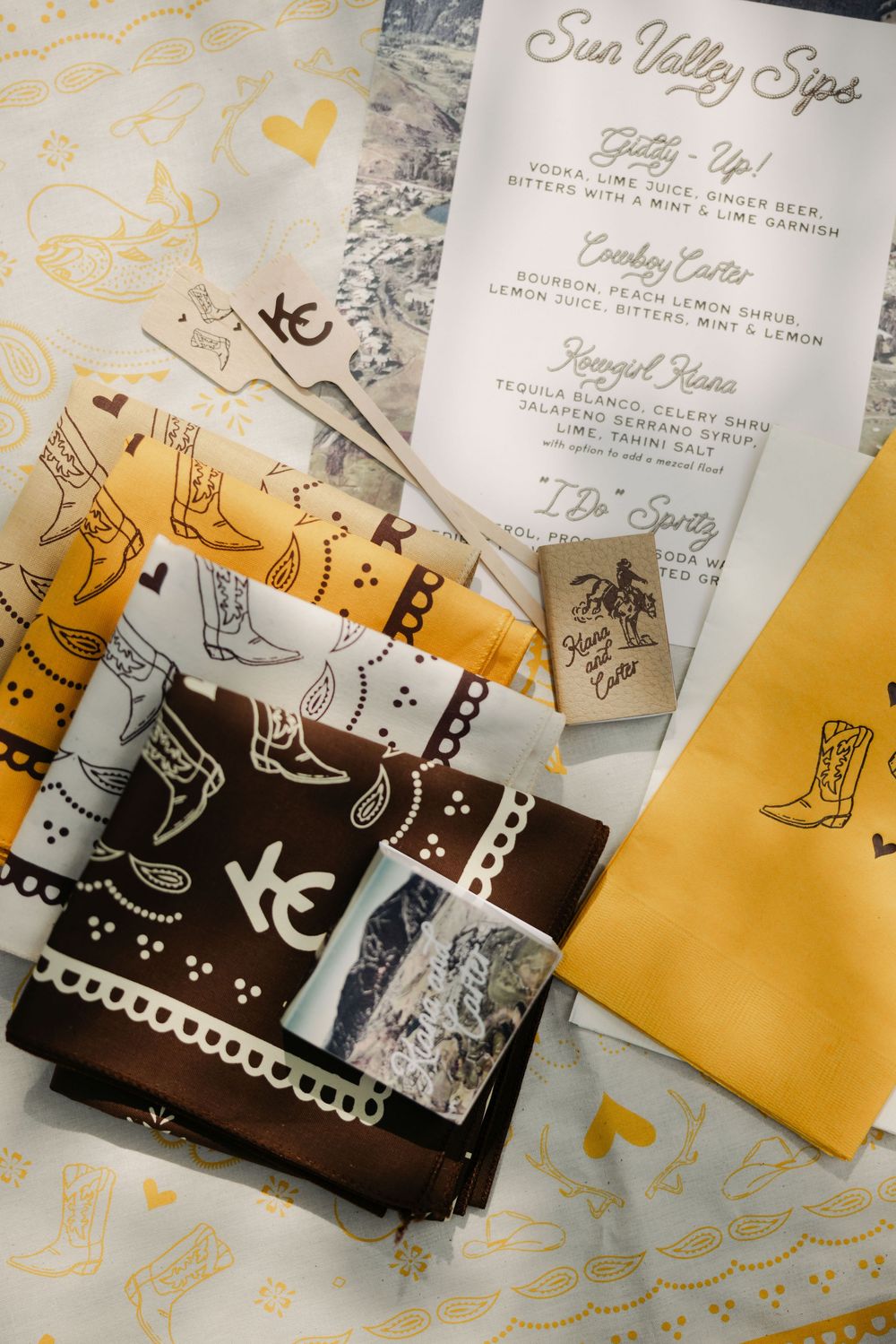 Wedding invitation suite featuring brown and yellow colors with whimsical cowboy boot illustrations and hearts.