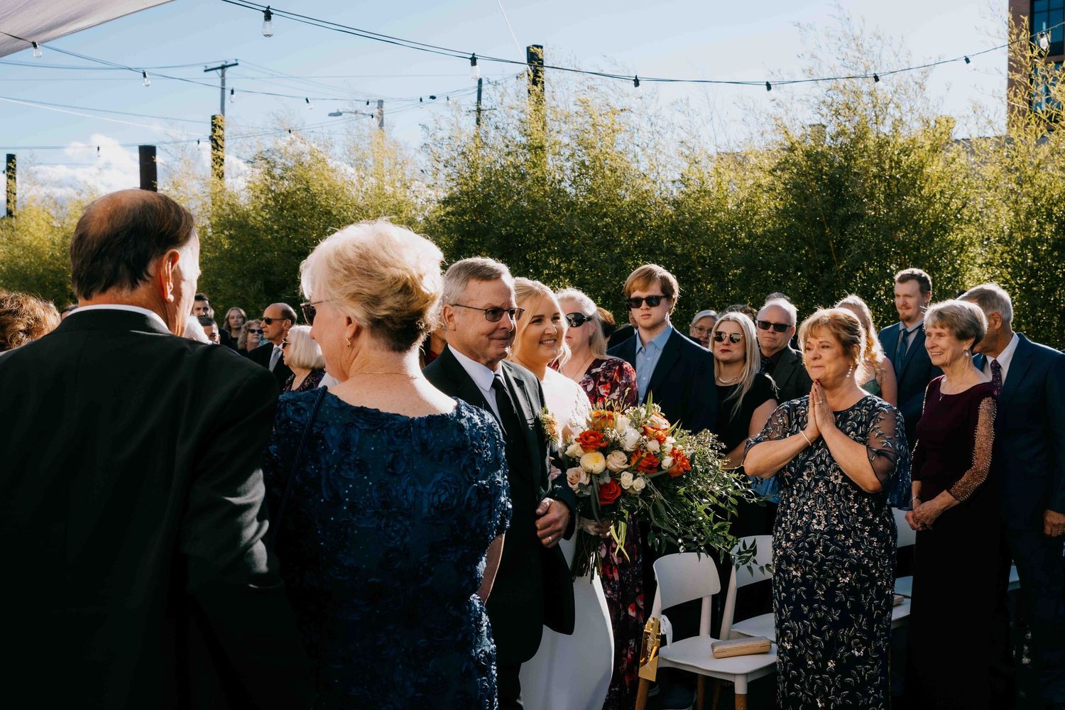 A father walks his daughter down the aisle as family and guests look on emotionally.