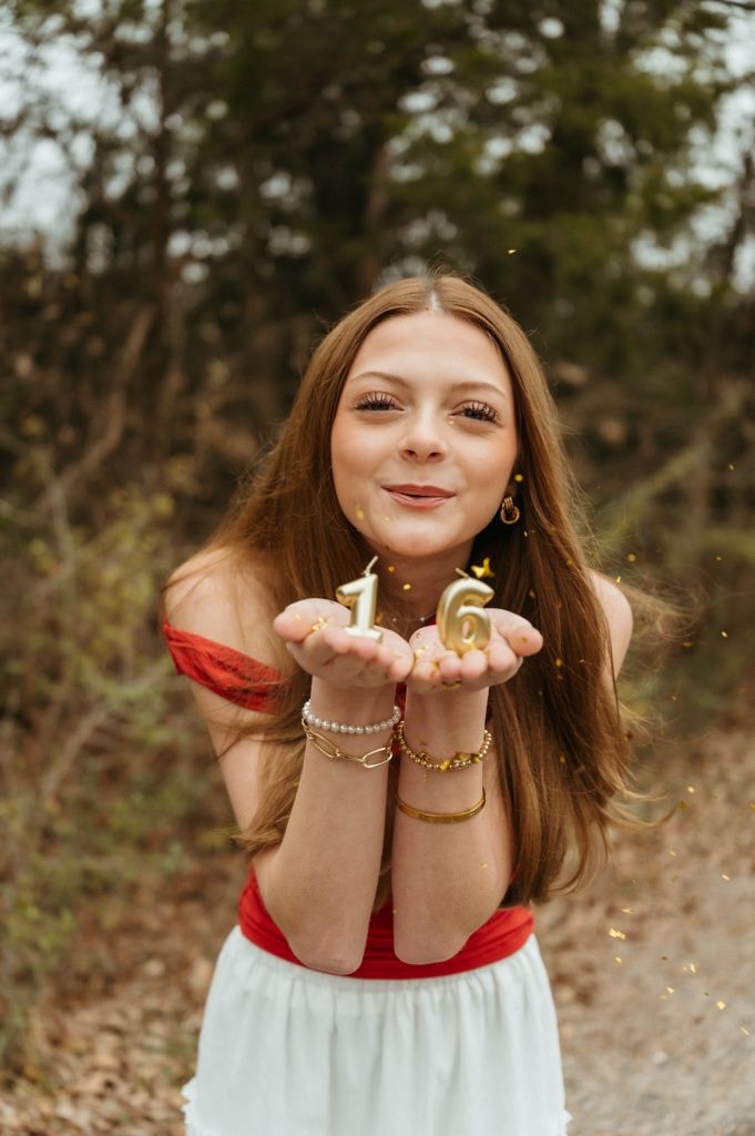 A person in red and white blows glitter from their hands in a magical autumn scene.