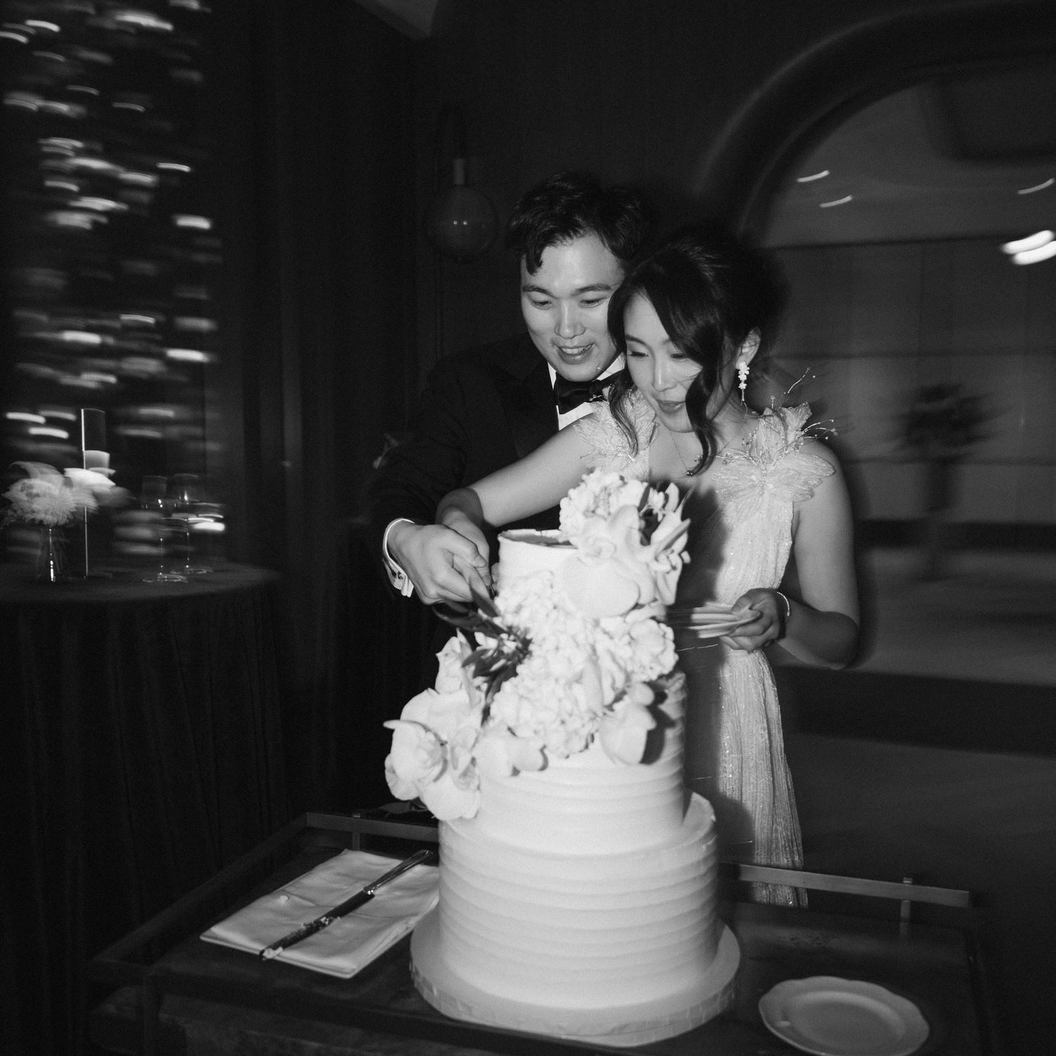 Black and white photos showing a wedding cake being cut and served at a reception.