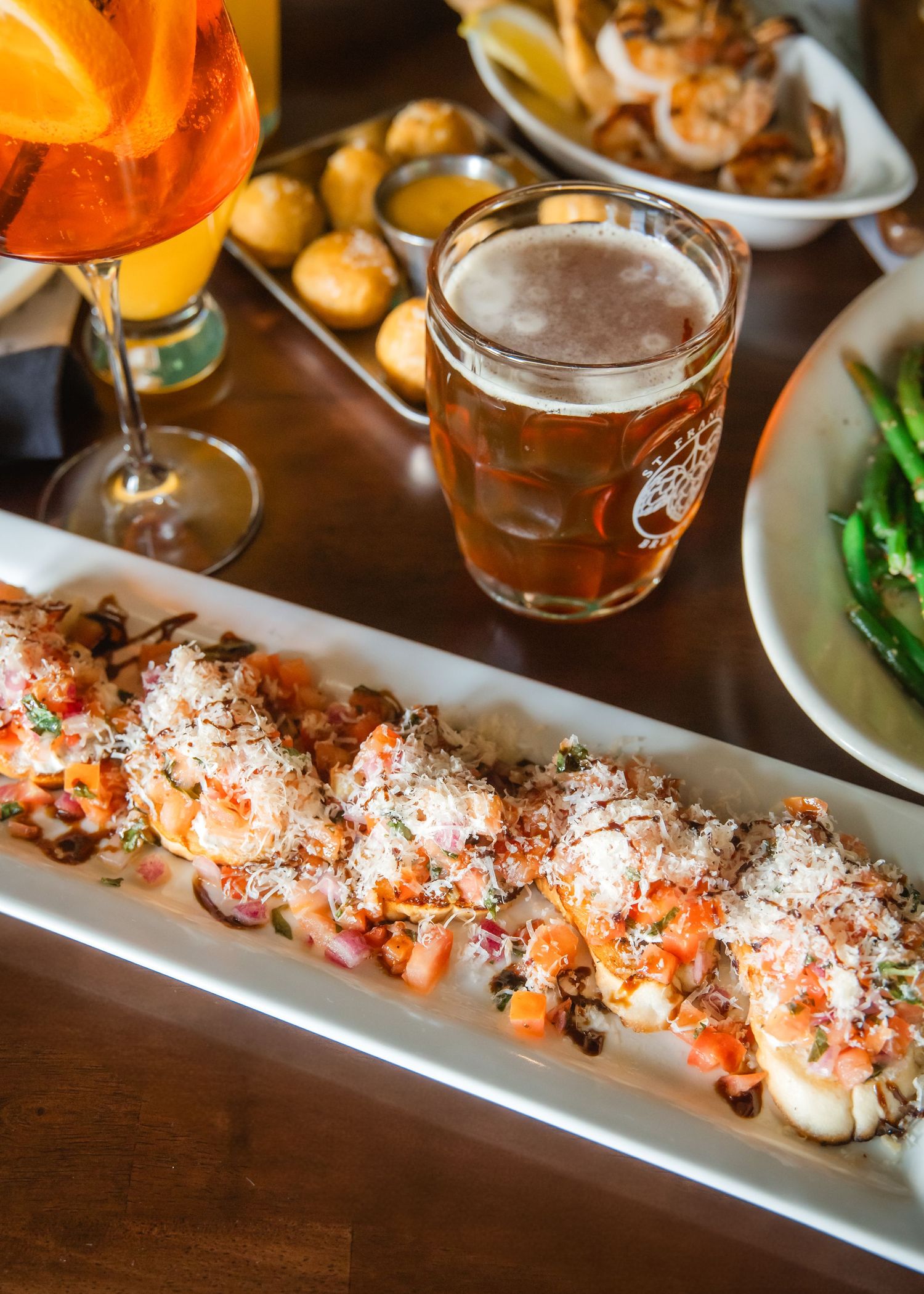 Long white platter of fresh salmon sushi rolls garnished with parmesan cheese and herbs on a wooden table.
