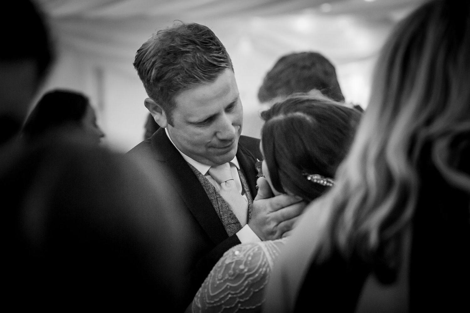 Emotional wedding moment between bride and groom surrounded by family and friends