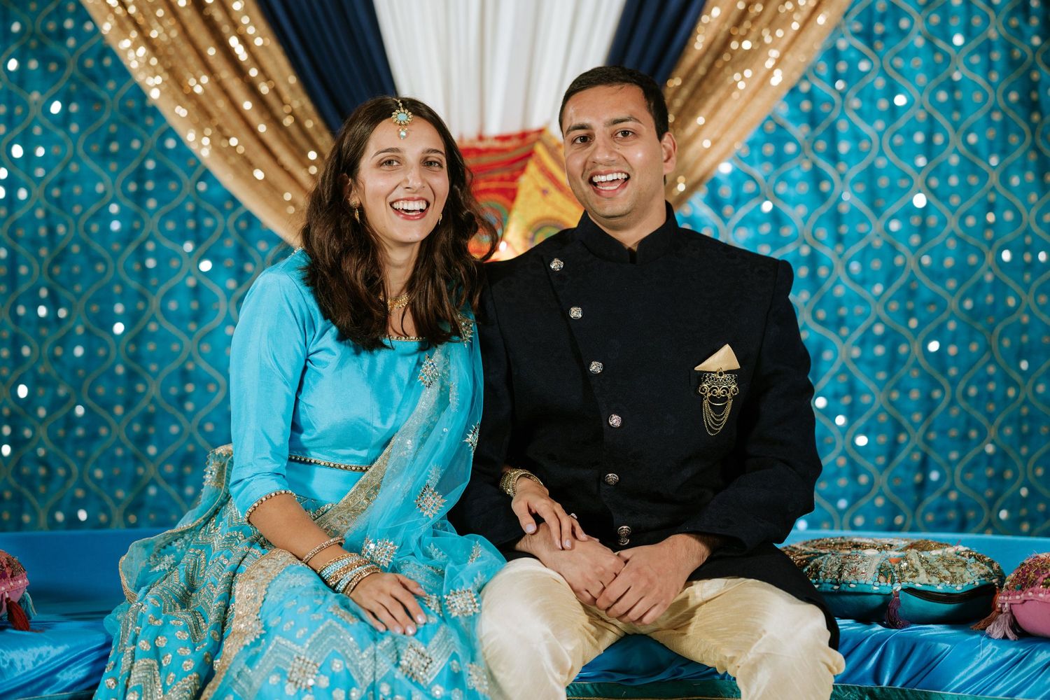 Couple poses together against sparkly blue backdrop during festive celebration photoshoot.