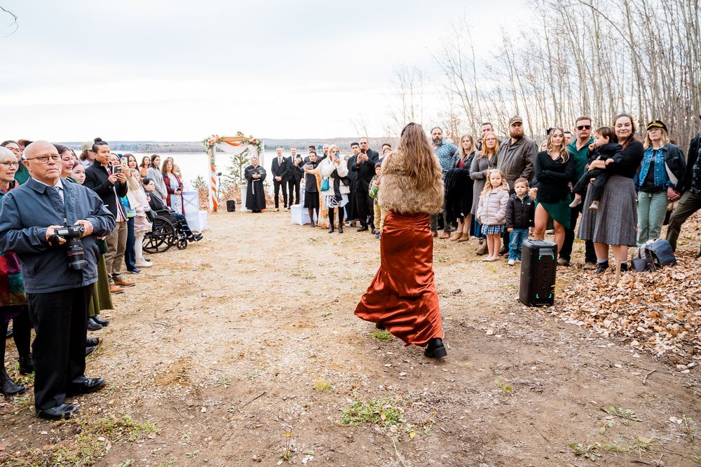 Wedding guests gather outdoors in a wooded area during an autumn ceremony. edmonton photographer
