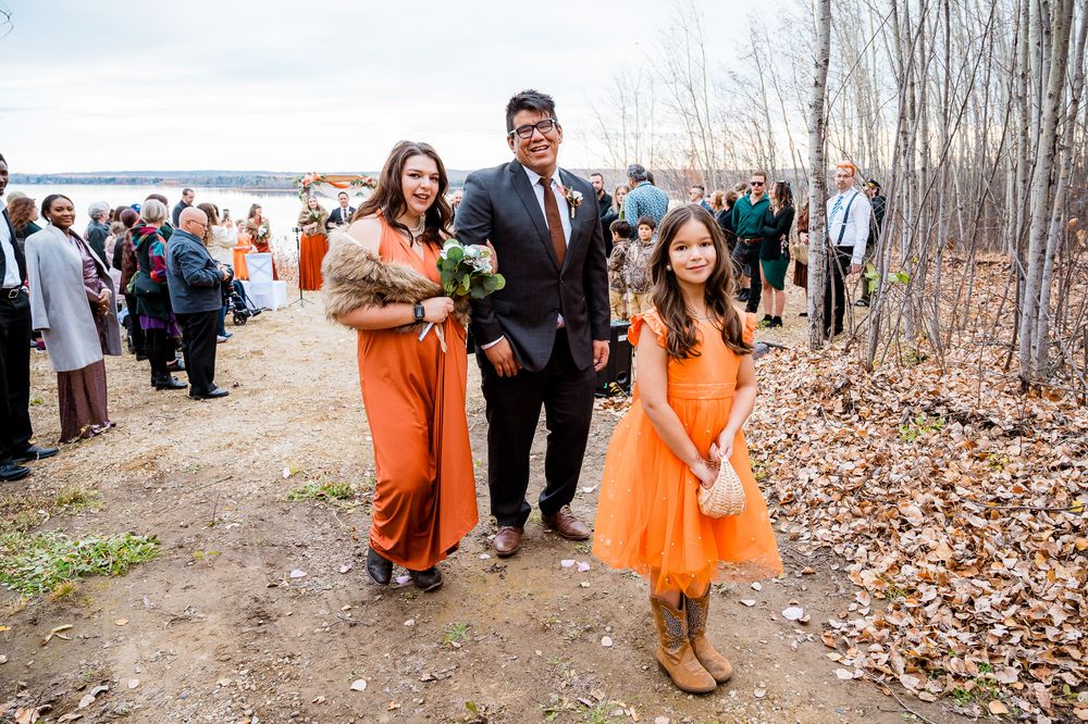 Wedding party walks through autumn woods with bridesmaids in bright orange dresses and groomsmen in dark suits. Seba beach