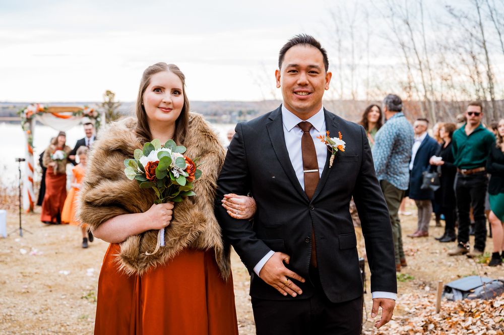 Bridal party poses together outdoors in orange and black attire during fall wedding celebration. Seba beach Village vows