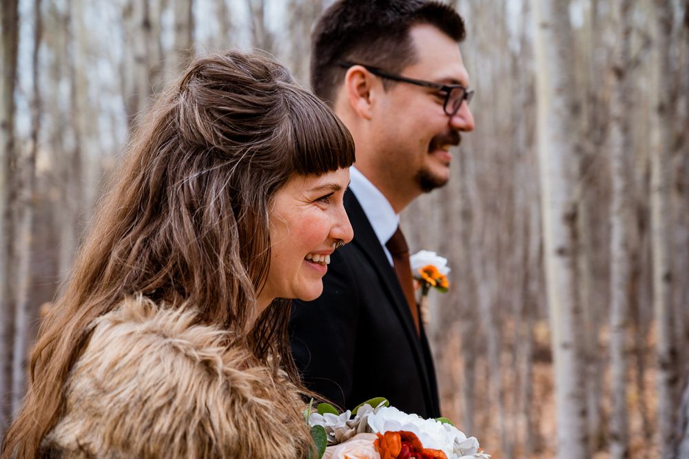 A happy couple shares a joyful moment during their fall wedding ceremony in a forest setting. reverend crystal rose sacred ceremony