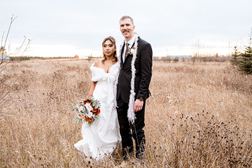 A couple in wedding attire embraces in a golden autumn field during their outdoor wedding photoshoot. Village vows seba beach wedding