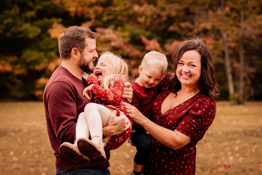 Parents holding their two children close while laughing during a fall family photoshoot in Bolsover, Ontario.