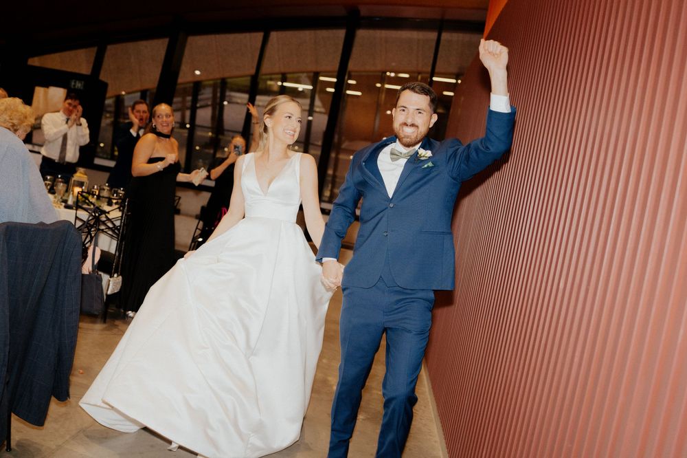 A couple dancing at a wedding reception with the bride in a white dress and groom in a navy blue suit.