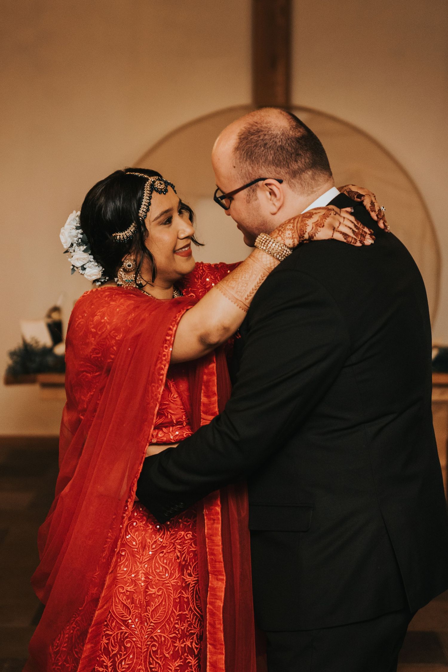 A couple shares an intimate dance moment in formal attire, with the bride wearing a stunning red sequined gown.