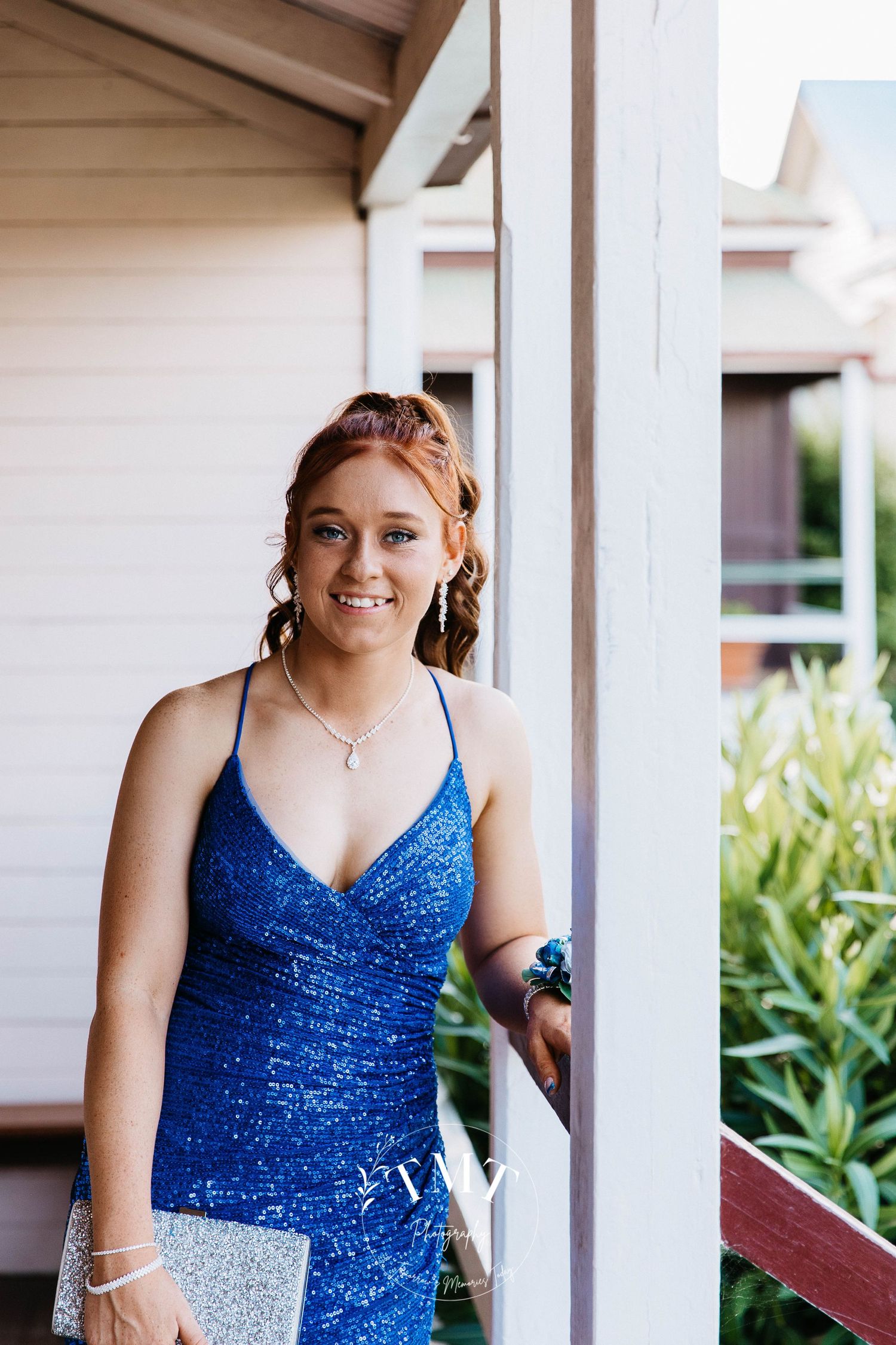 Graduate standing on a verandah  during a professional formal photo shoot.
