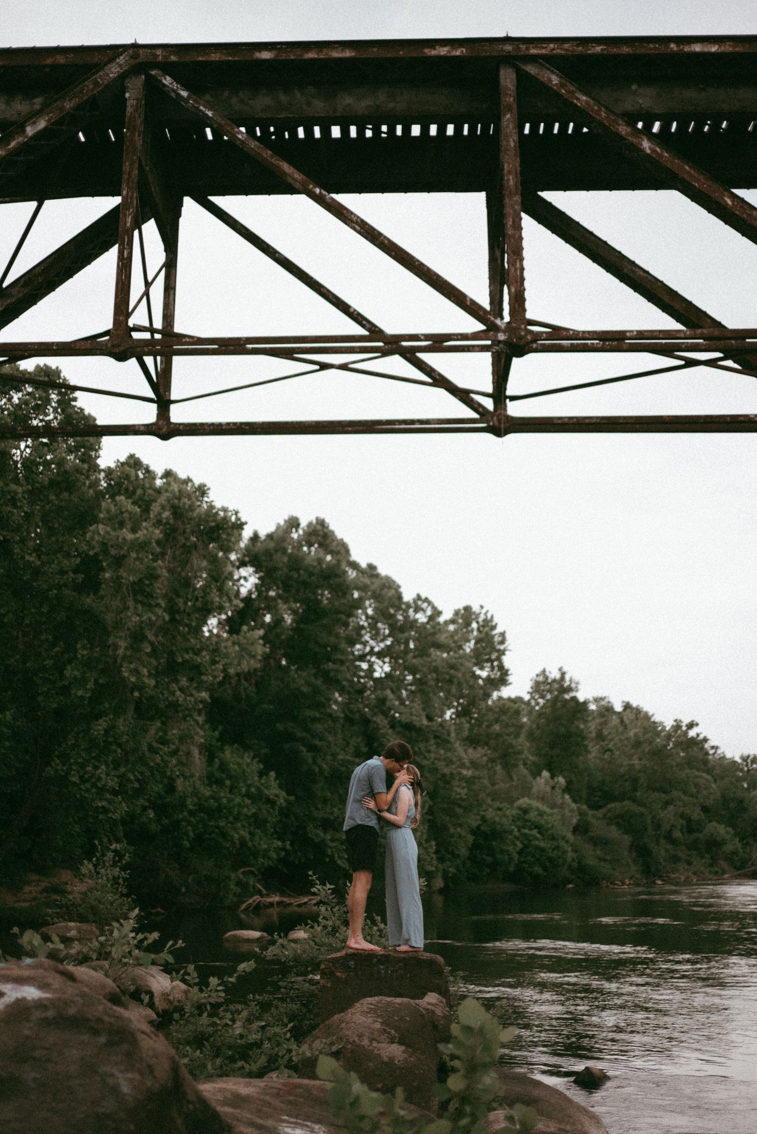 Couple kissing underneath a bridge where they got engaged