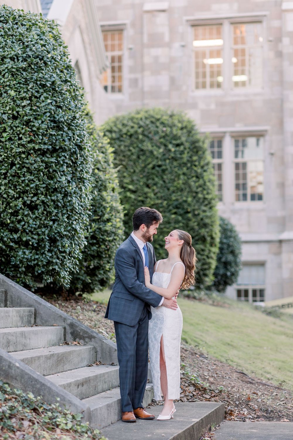 Couple sharing a romantic moment on stone steps outside a classic stone building.