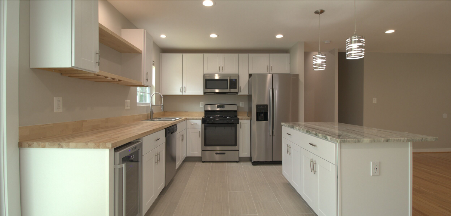 Sleek modern kitchen with white cabinets, stainless steel appliances, and recessed lighting.