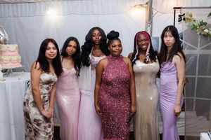 A group of people wearing formal pink and burgundy dresses pose together at an elegant event.