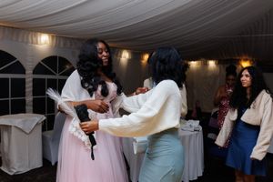 Guests dancing together at an indoor wedding reception under white draped fabric ceiling decorations.