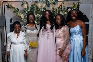 A group of people wearing pastel and white dresses pose together at a formal event.