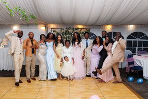 Wedding reception guests dancing and celebrating on a wooden dance floor under a white tent.
