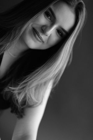 Close-up black and white portrait with soft lighting highlighting blonde hair and gentle expression.