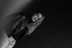 Artistic low-key portrait in black and white with dramatic shadows.