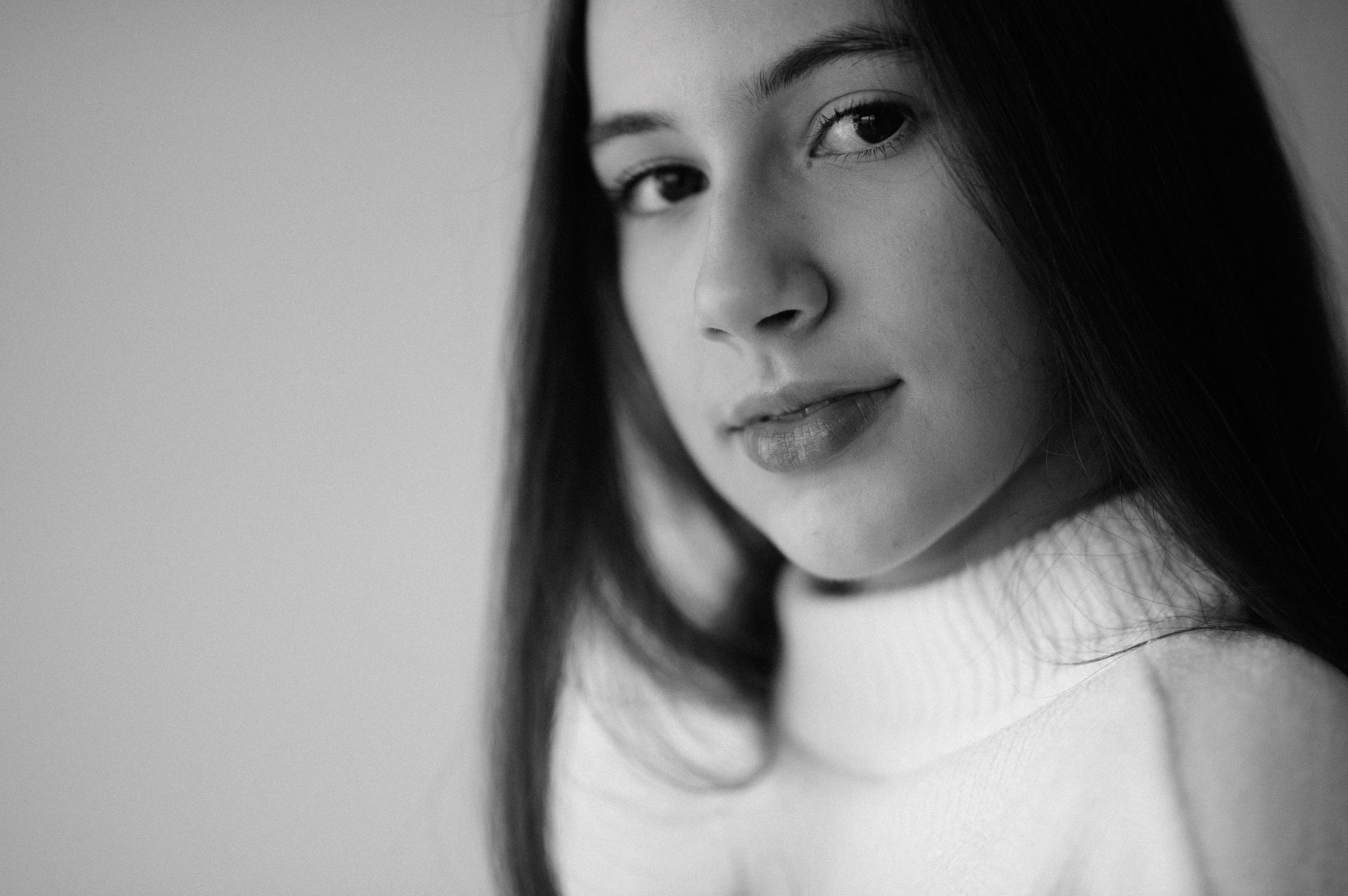 Classic headshot in white turtleneck sweater with soft natural lighting.