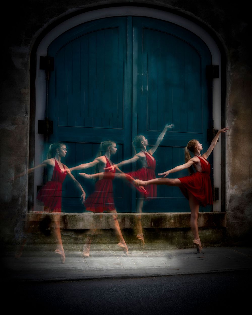 Four dancers in red dresses perform synchronized movements against blue door backdrop.