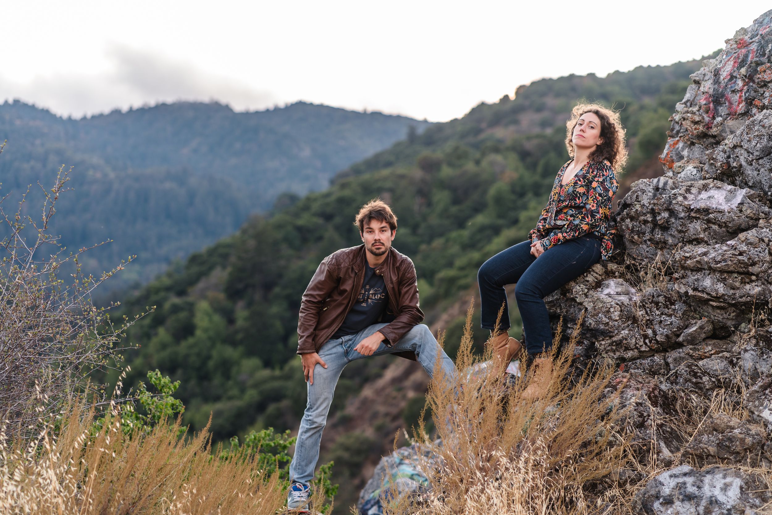 Couple rests on rocky outcrop during mountain hike with scenic views. Located near Felton.