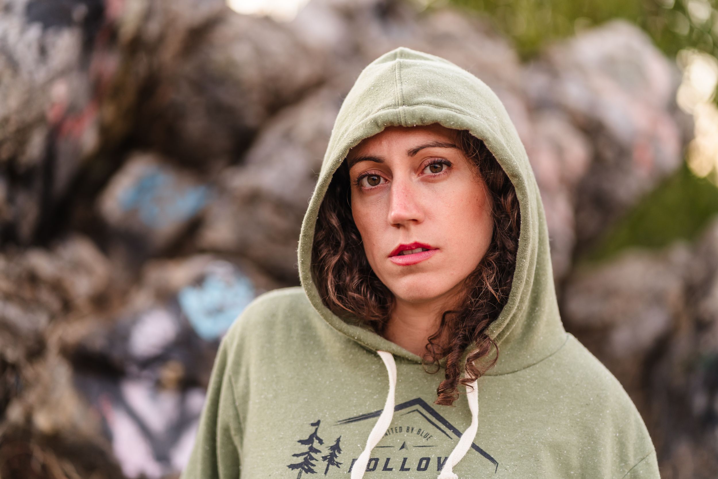 Person wearing mint green hoodie poses against rocky background in outdoor portrait. Located near Felton.