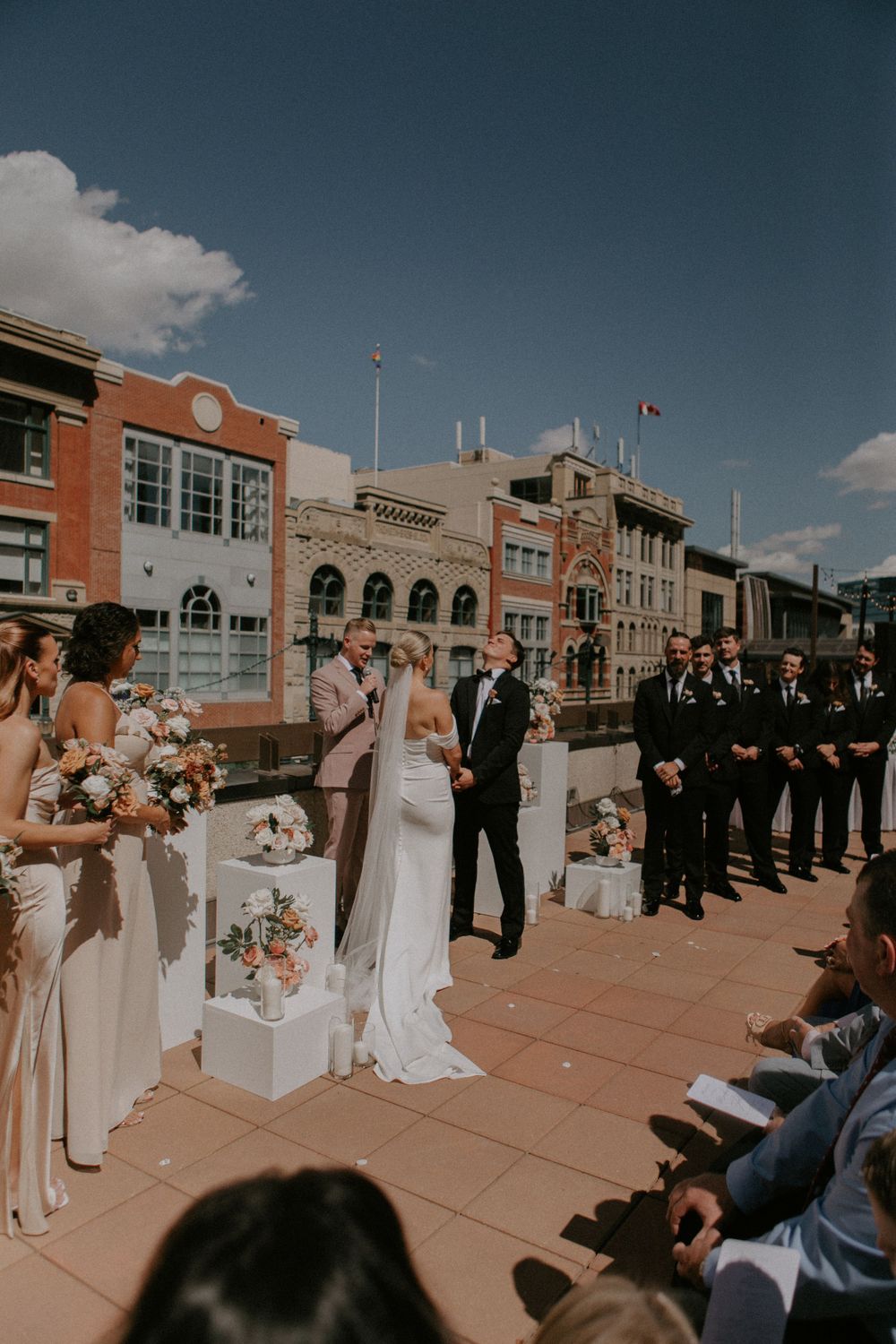 Outdoor wedding ceremony on rooftop with city buildings in background and floral decorations.