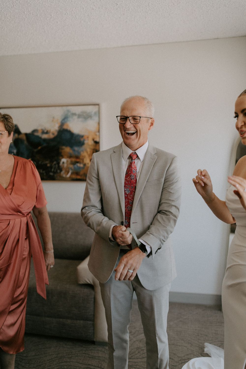People celebrating in a bright room with joyful expressions, featuring formal attire and a modern interior.