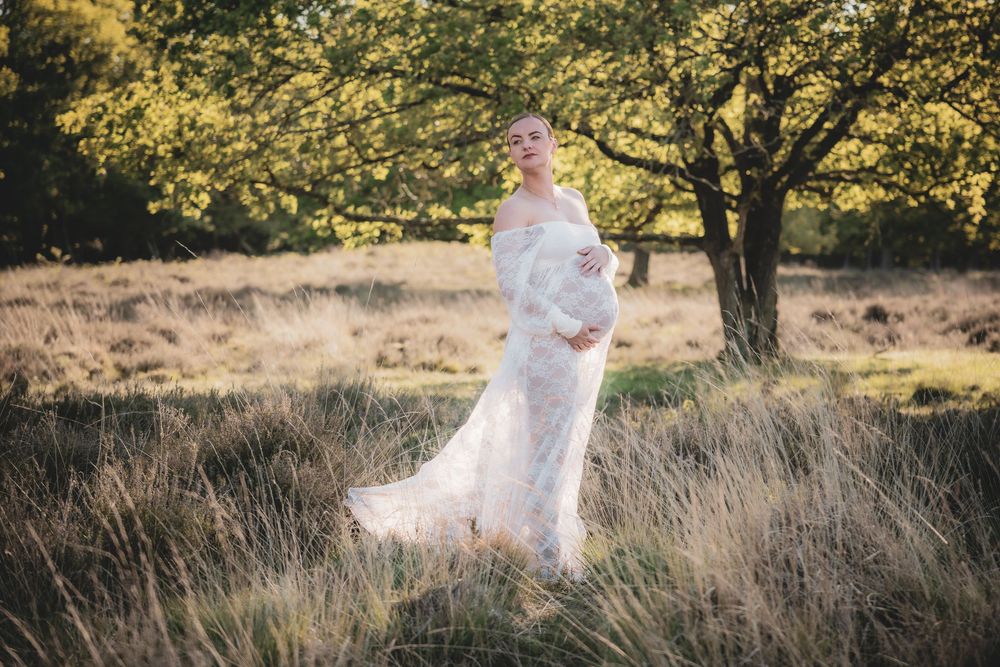 A flowing white dress catches the sunlight in a dreamy meadow setting with tall grass and autumn trees.