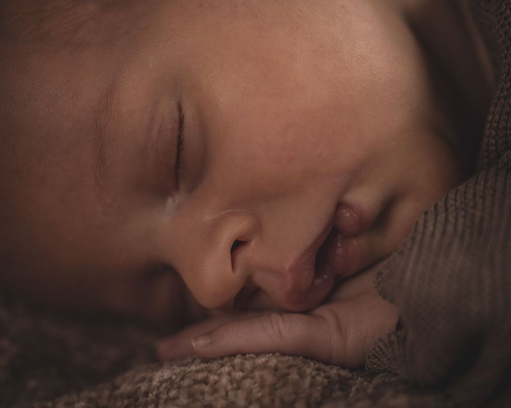 Een serie close-upfoto’s van een slapende baby, gewikkeld in zachte stoffen.