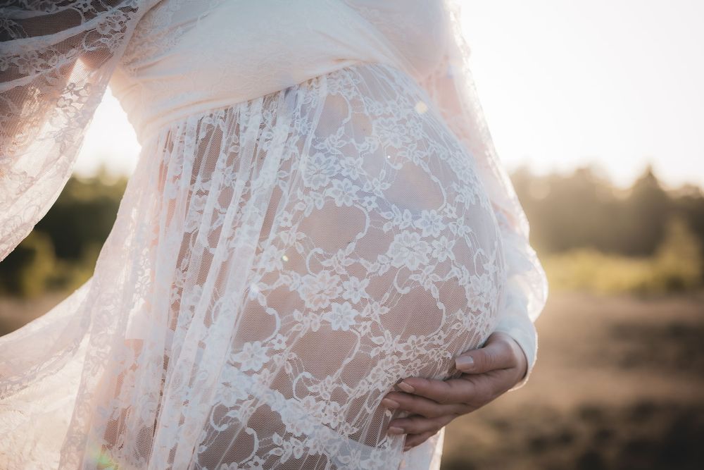 A close-up view of delicate white lace fabric on a dress with sunlight glowing through in a natural outdoor setting.