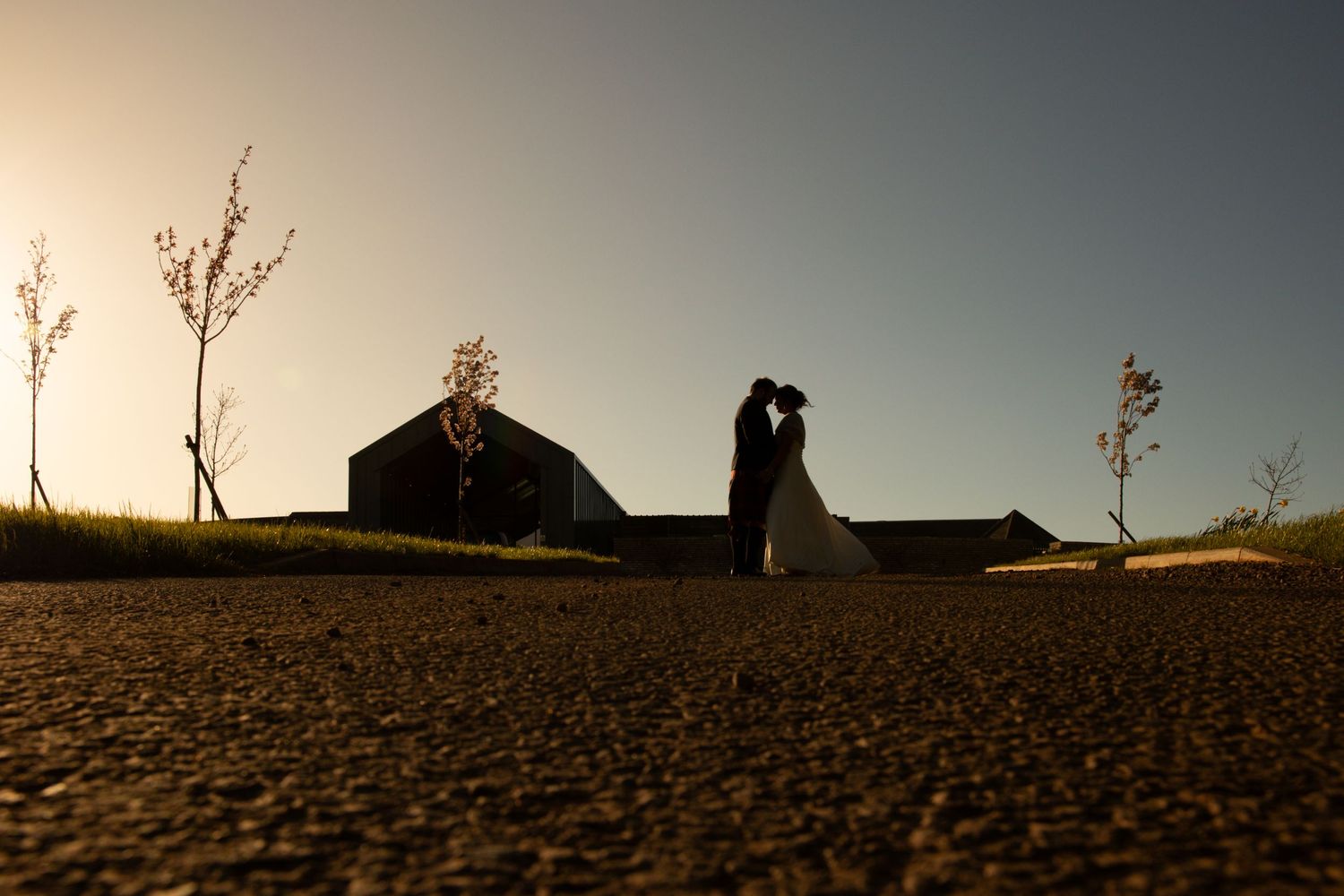 Silhouetted couple against sunset sky in dramatic landscape composition.