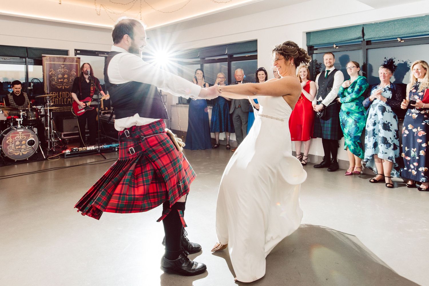 Dancers in wedding attire perform energetic moves during a Scottish-themed celebration.