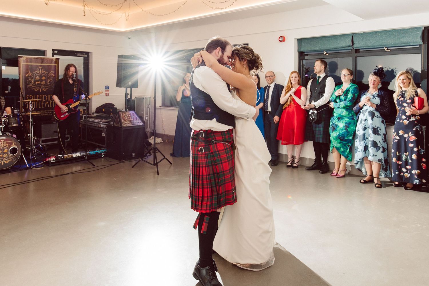 Dancers perform traditional moves in a modern reception venue with large windows.
