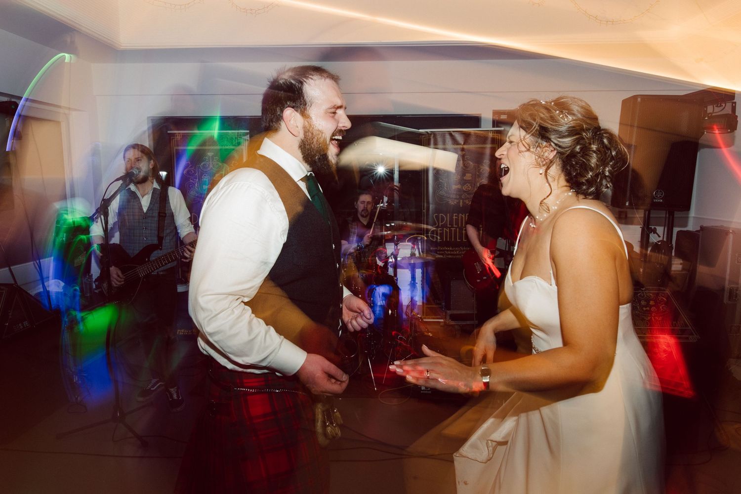 Wedding reception dance party with colorful lighting and guests celebrating.