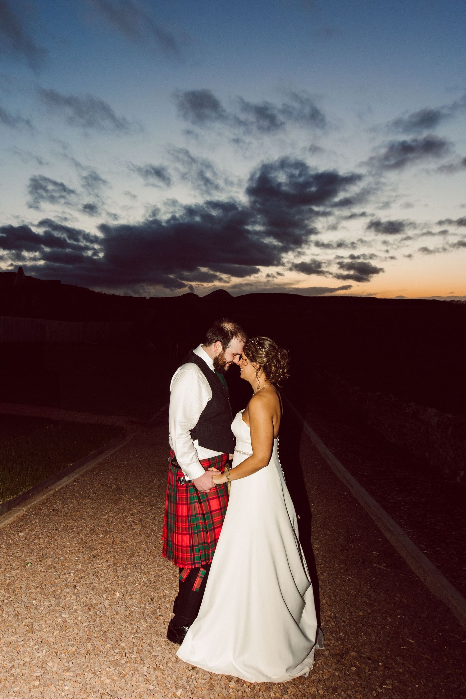 Romantic sunset photoshoot with couple on rural road at twilight.