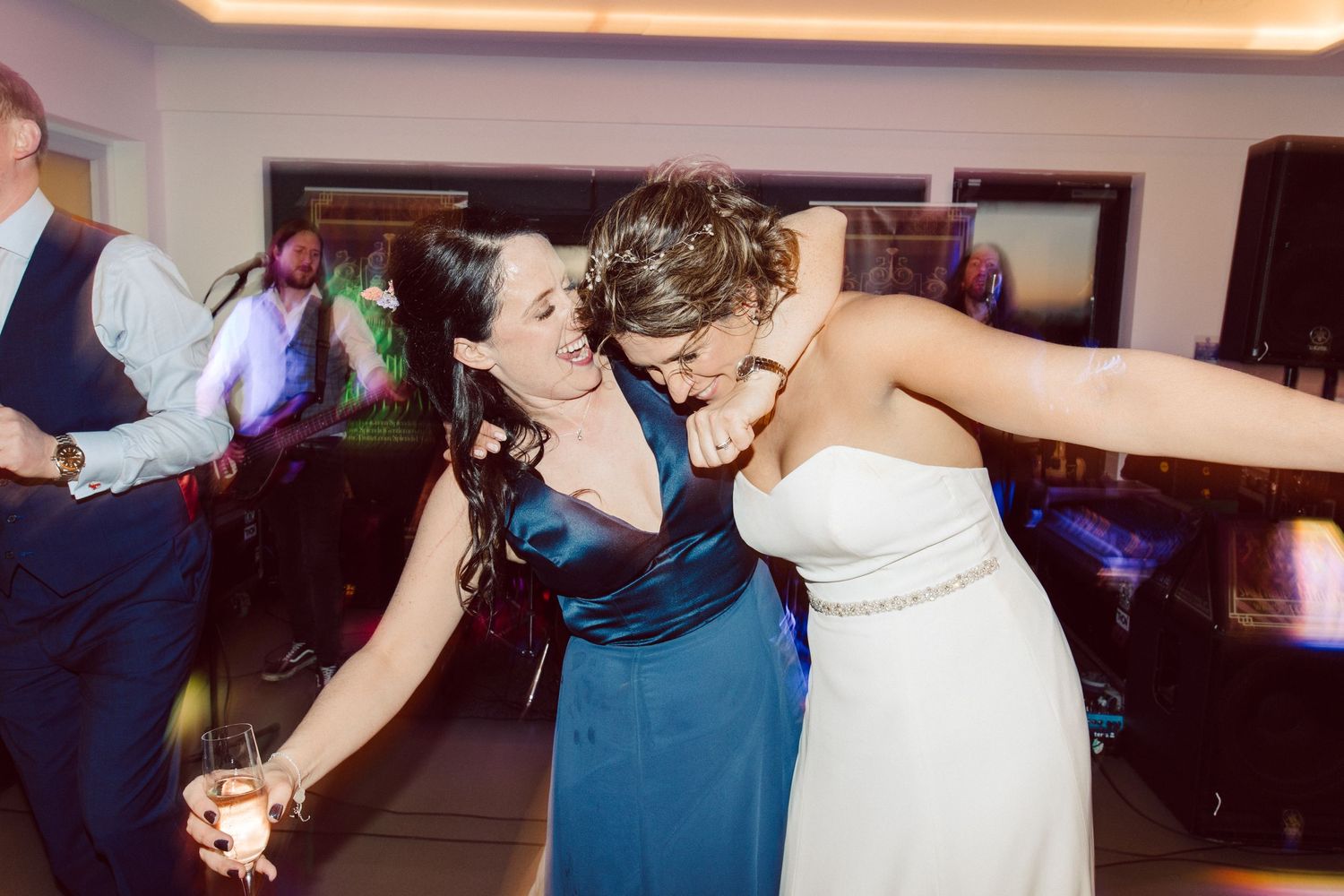 Wedding guests dance and celebrate on a dimly lit dance floor.