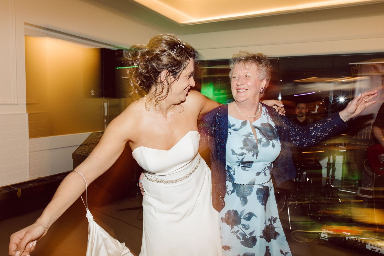 Wedding celebration with guests dancing enthusiastically under warm lighting.