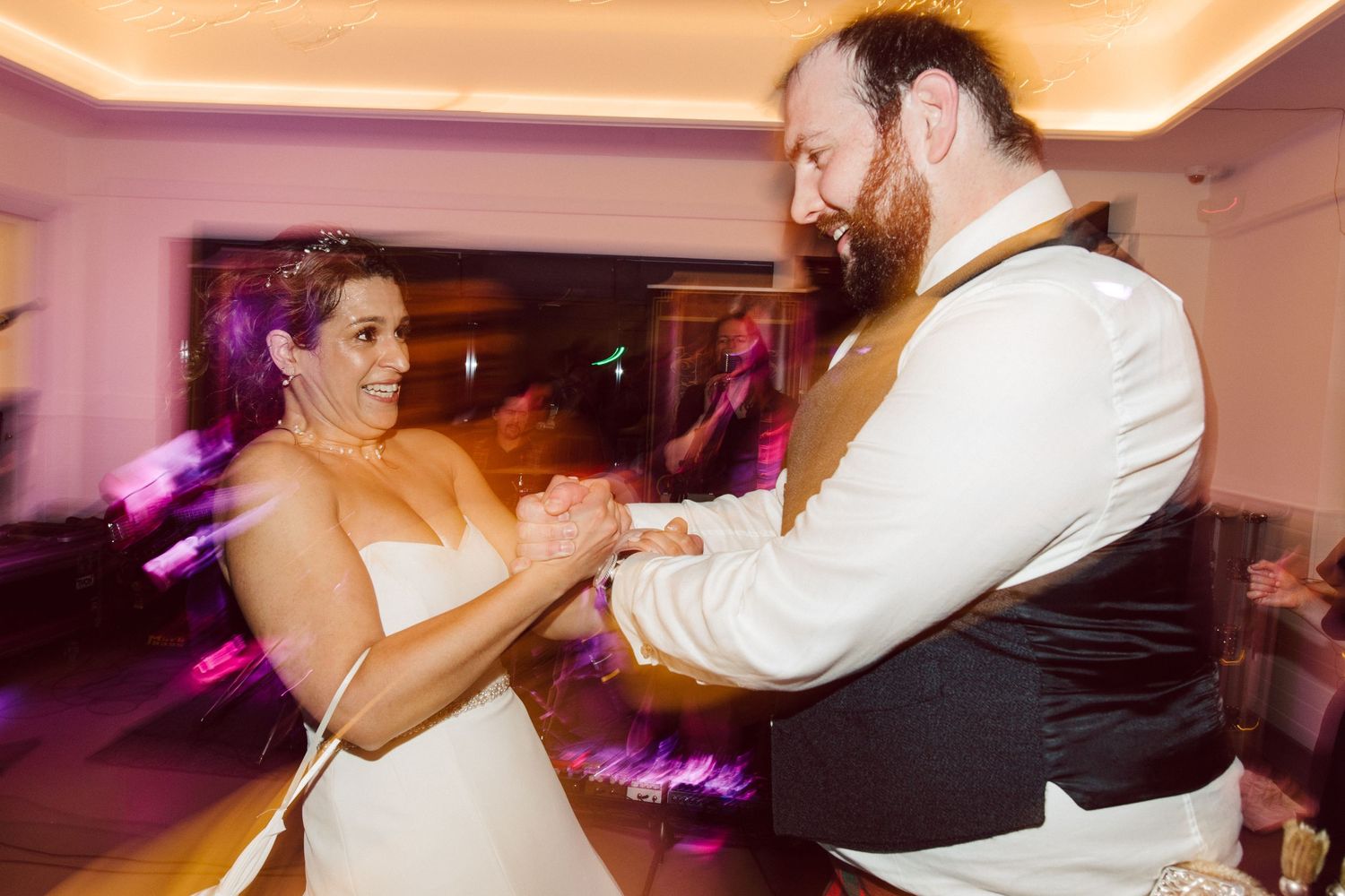 Couples dancing together on an illuminated dance floor at an evening wedding reception.