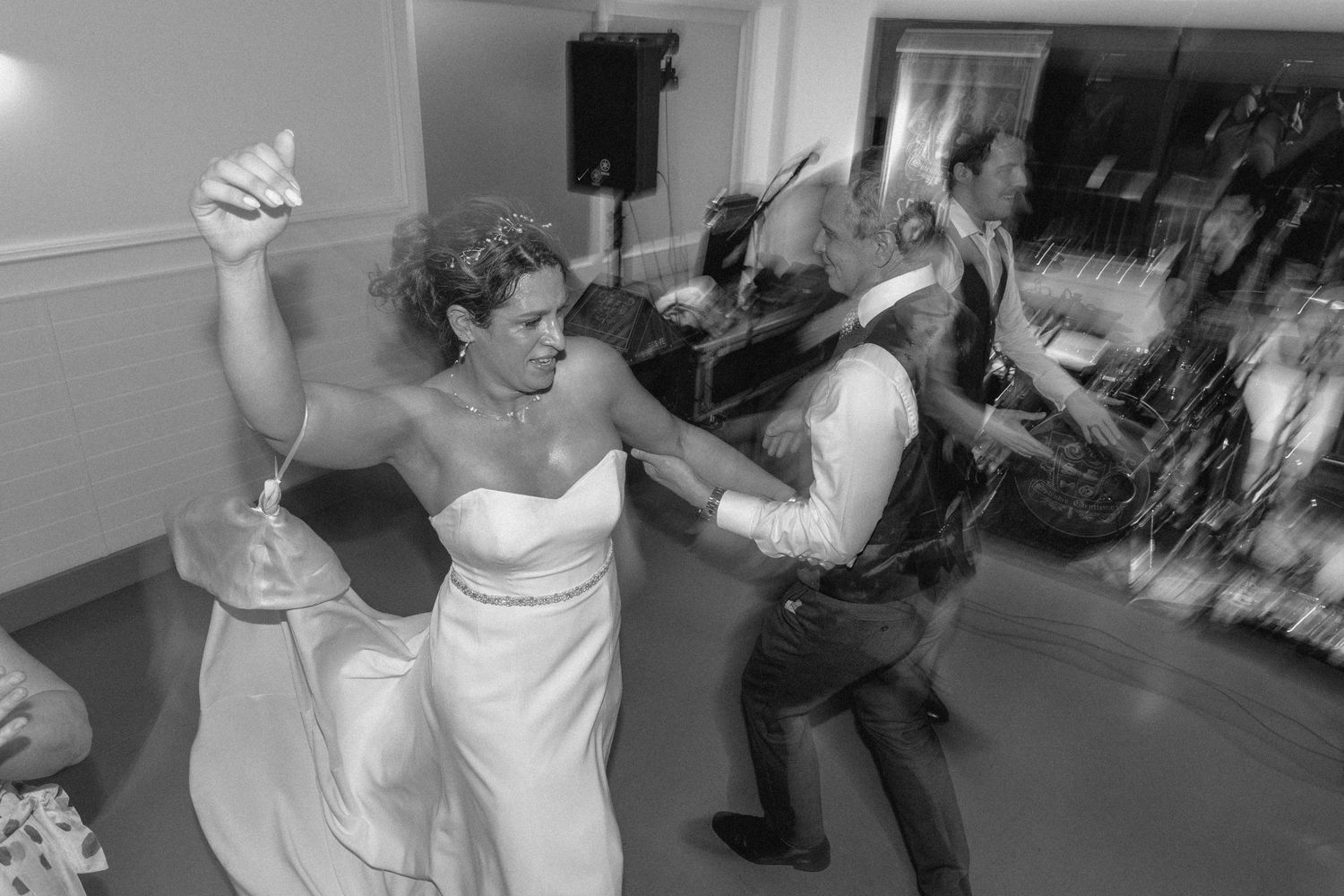 Black and white photo of wedding guests dancing and celebrating on the dance floor.