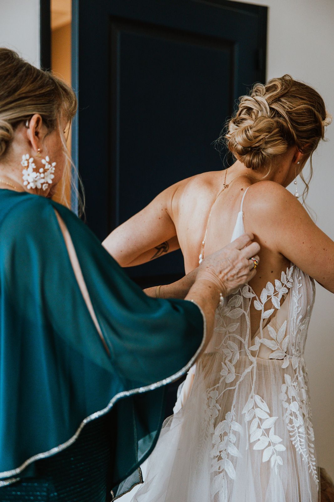 A sequence of photos showing someone helping another person into an elegant white lace wedding dress with floral details.