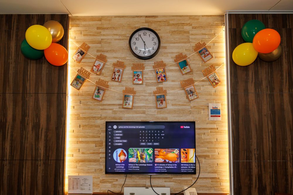Party room decorated with colorful balloons and banners around a mounted TV screen.