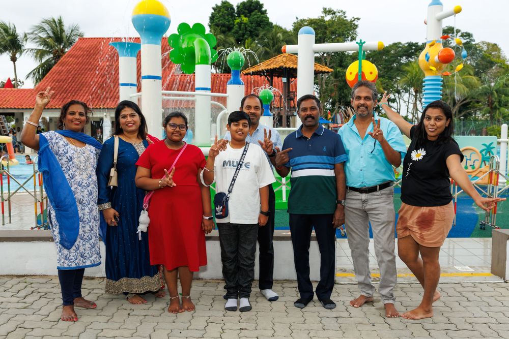 Group photo of people posing together at a festive outdoor venue with colorful balloons.